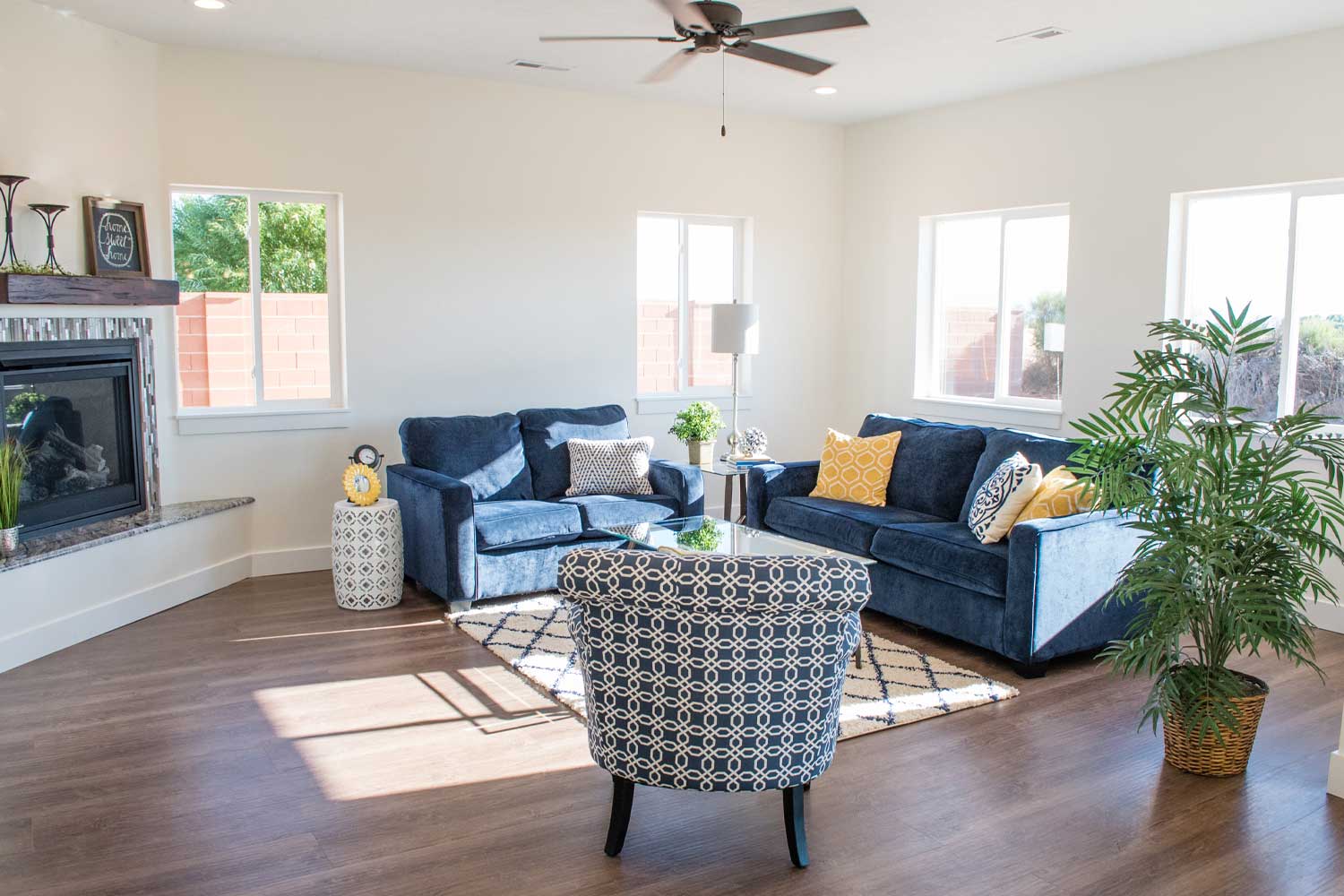 brightly lit living room with fireplace, blue furniture and hard wood floors