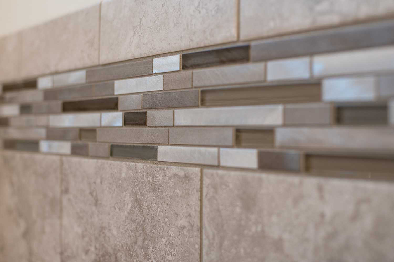 6 inch strip of shower tiles of multiple shades of brown