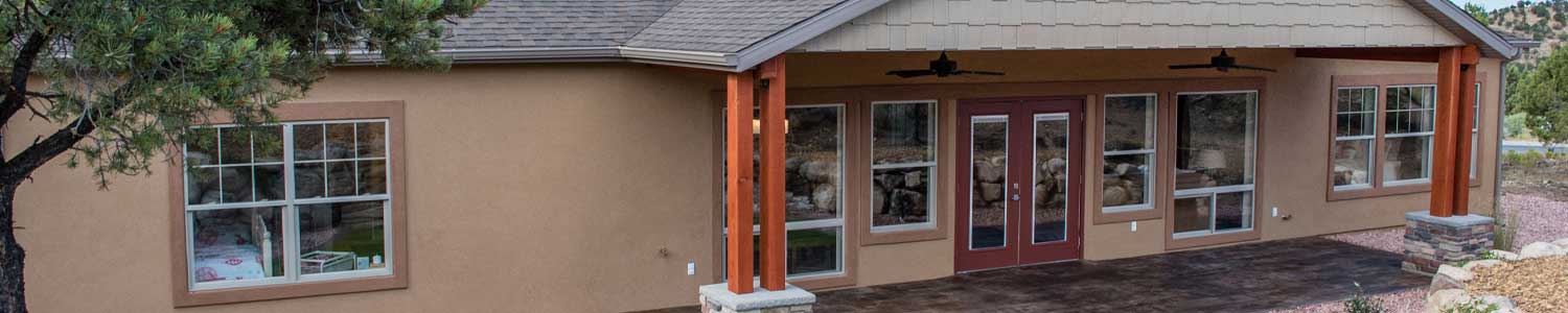 backside view of stucco home with patio opening from living room