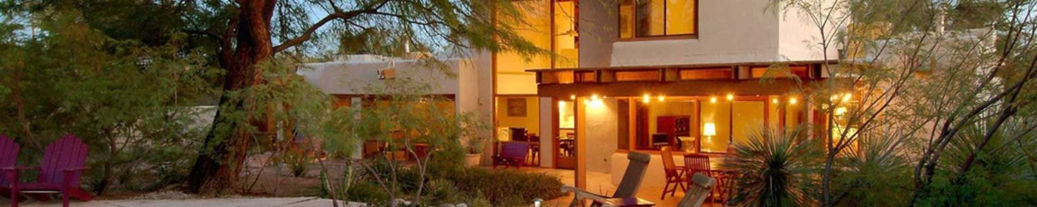 stucco exterior of new home at night and outdoor patio and natural landscaping