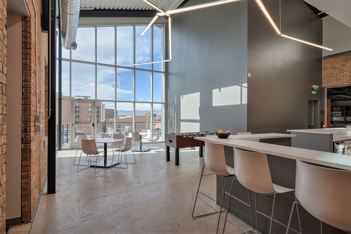 modern workplace break area with bar seating and large floor‑to‑ceiling windows