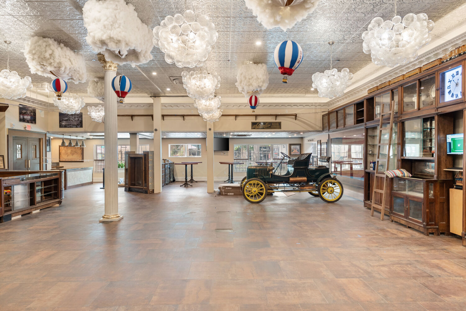 Interior of the Stanley Chocolate Factory gift shop featuring vintage display cabinets, themed cloud and hot‑air‑balloon light fixtures, and open retail space with historic decorative elements.