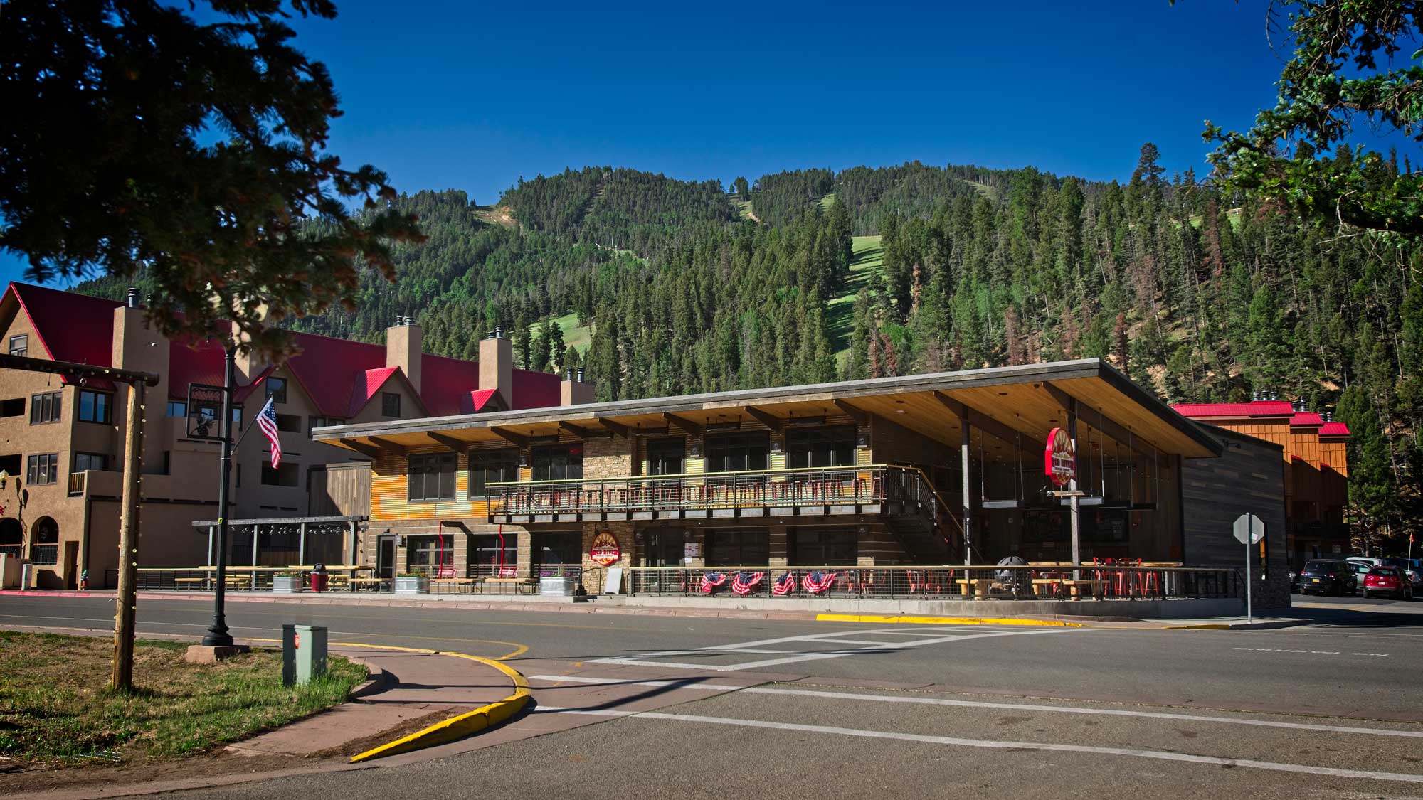 Exterior view of RRBC, a modern commercial building with a rustic design featuring wood, metal, and glass elements. The structure is surrounded by landscaping and outdoor seating, creating an inviting and contemporary atmosphere.